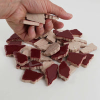 Video of Flip XL ceramic puzzle pieces in old pink, opaque glazed porcelain, 20–60 mm, picked up from a pile by hand and dropped back to show their size, shapes and finish