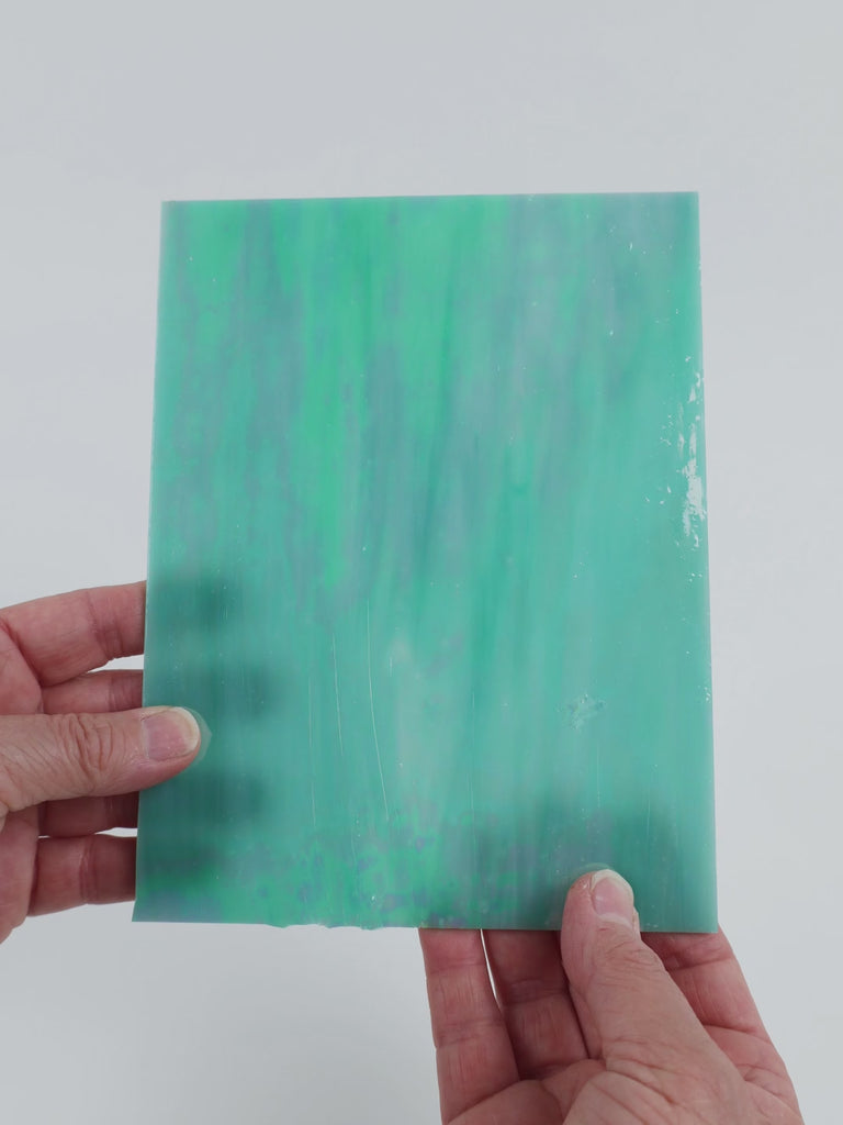 Video of the Pale Teal Iridised glass plate in iridised translucent teal, 15x19cm, held up and tilted to show its pattern and transparency